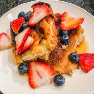 single serving of creme brulee french toast with berries and syrup