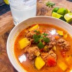 picture of albondigas soup with a margarita and lime slices
