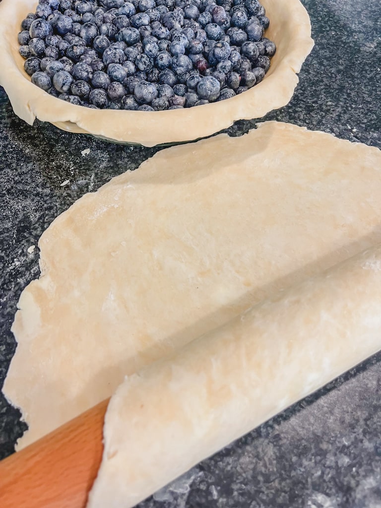 rolled out pie crust ready to be placed on top of blueberries