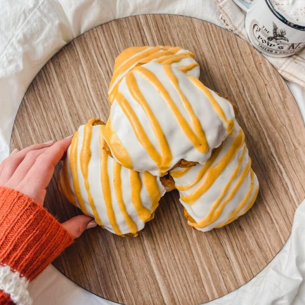 overhead picture of hand reaching for a pumpkin scone on plate