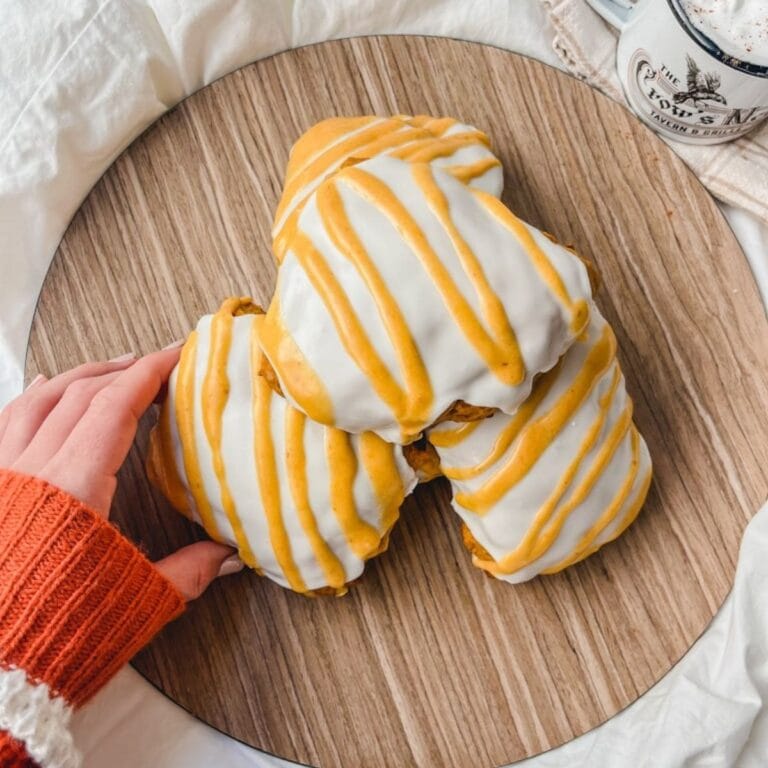 overhead picture of hand reaching for a pumpkin scone on plate