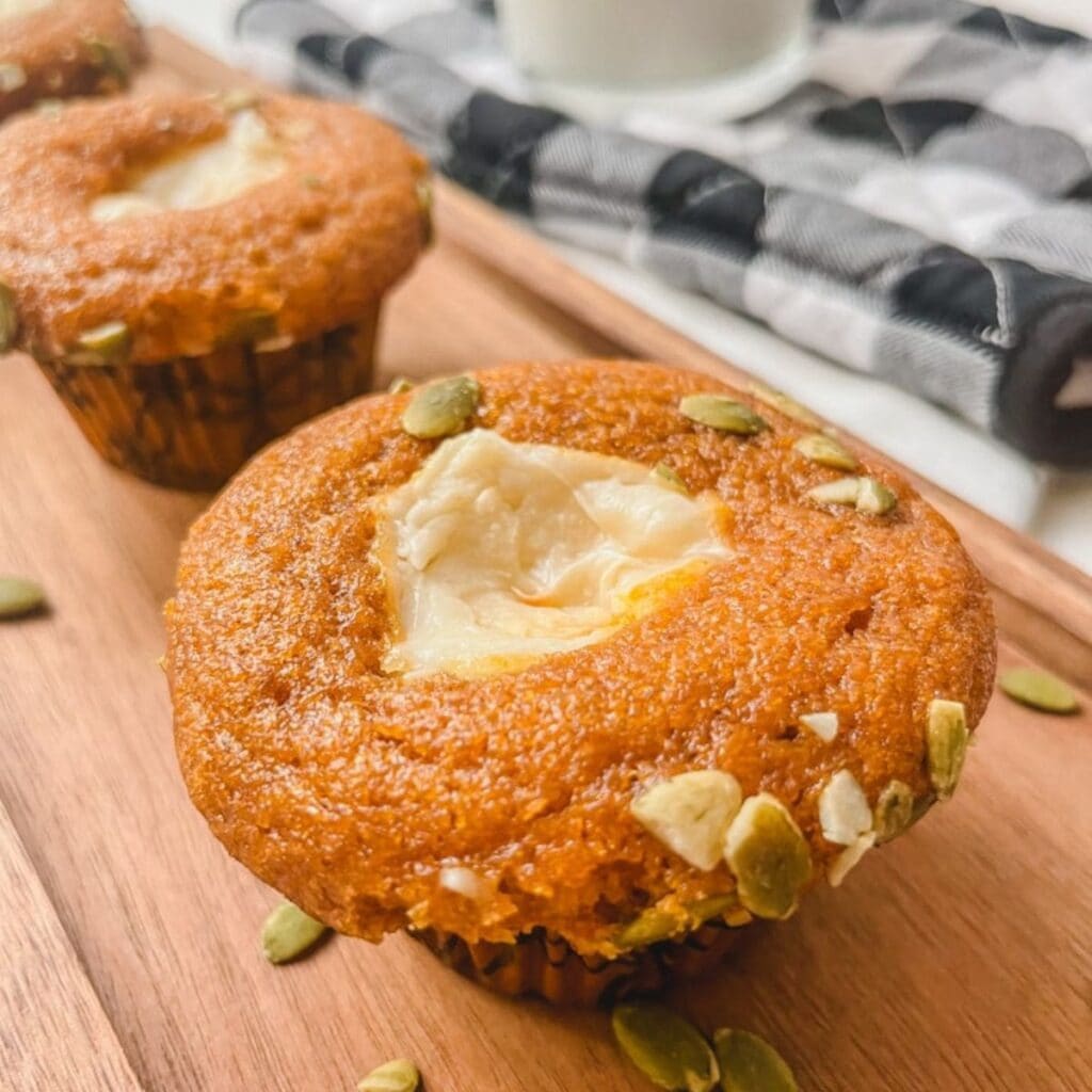 close up of pumpkin cream cheese muffin on wooden platter