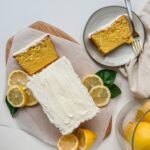featured image of starbucks iced lemon loaf copycat recipe on a serving board with a slice of loaf on a plate with a fork and fabric napkin