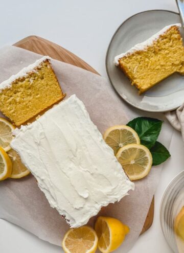 featured image of starbucks iced lemon loaf copycat recipe on a serving board with a slice of loaf on a plate with a fork and fabric napkin