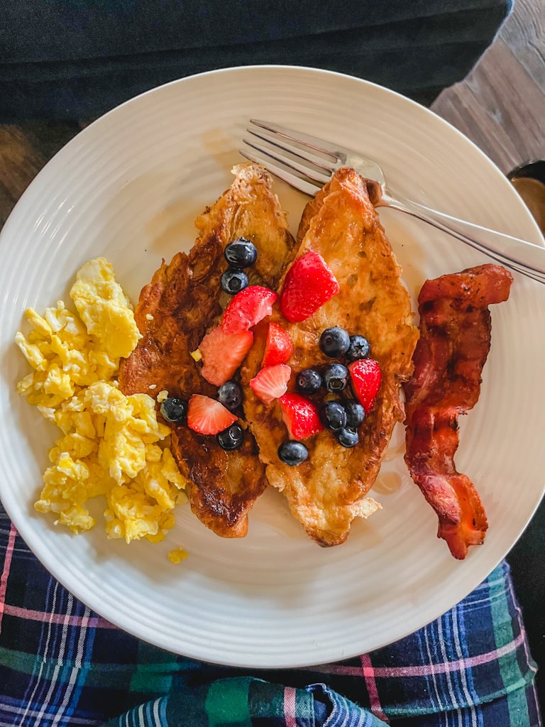 overhead picture of plated butter croissant french toast with scrambled eggs and bacon