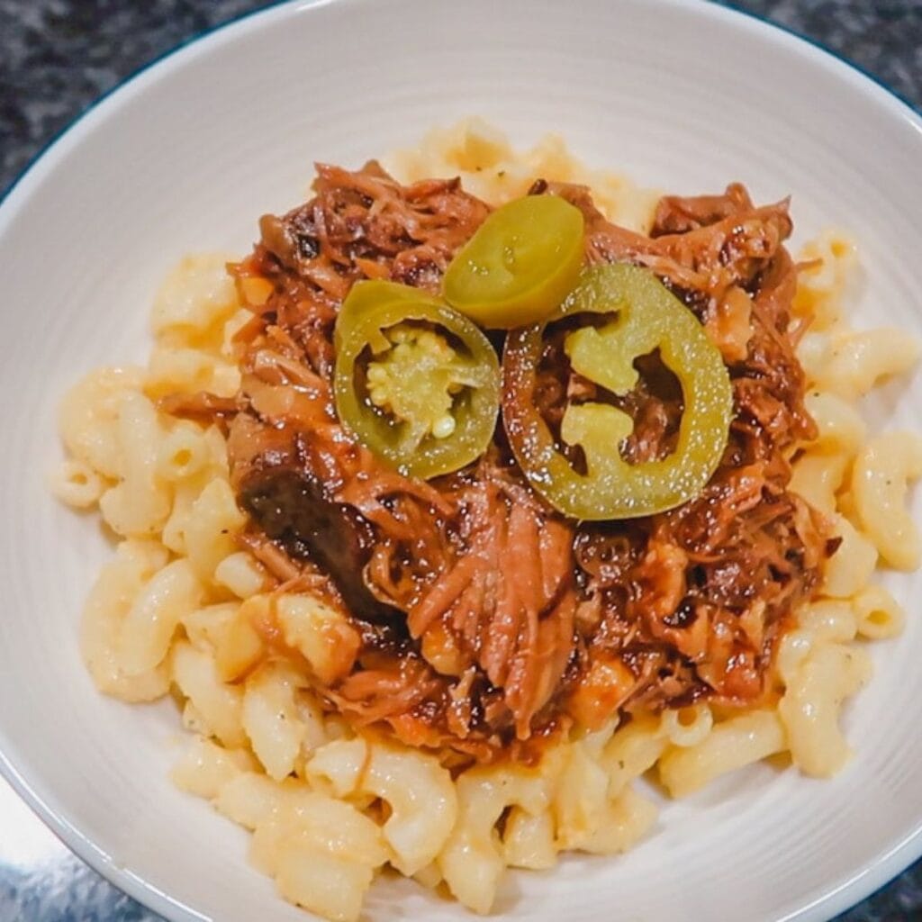 slow cooker pulled pork on top of creamy mac and cheese with jalapenos