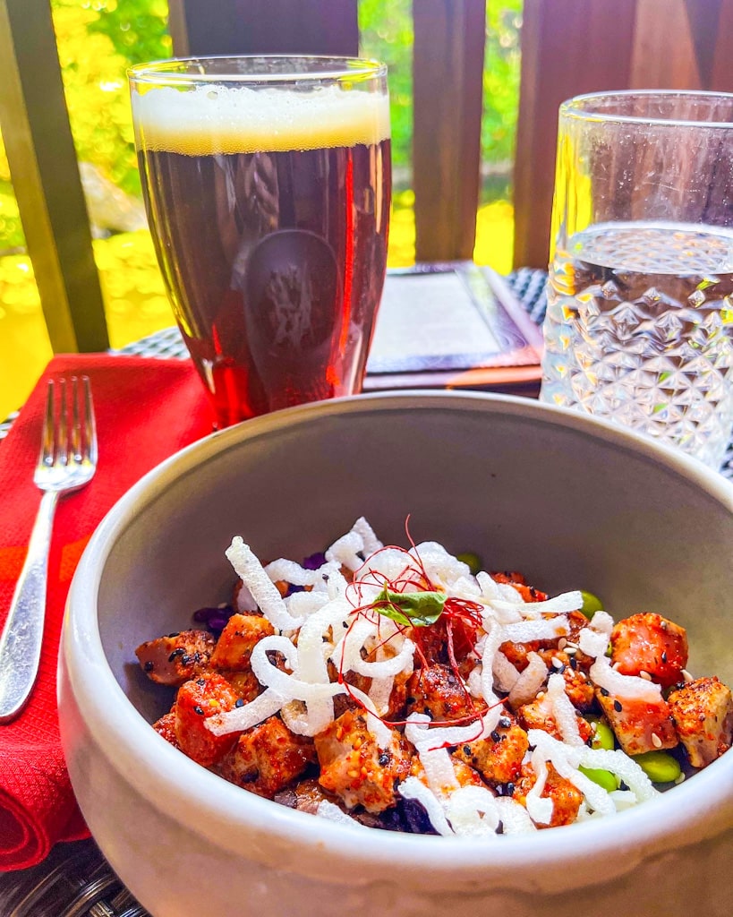 close up of chicken bowl and glass of beer on an outside table at the Nomad Lounge while visiting disney world solo