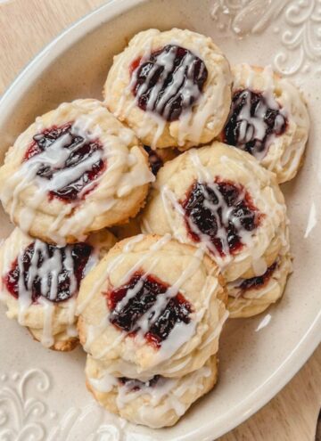 overhead picture of several glazed cherry almond cookies on a platter sitting on top of a cutting board