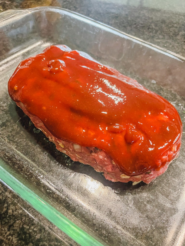 classic ground beef meatloaf with ketchup glaze about to be placed in oven to cook.