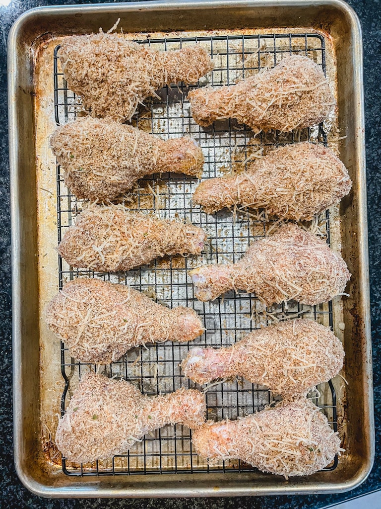 overhead picture of 10 chicken drumsticks on a lined baking sheet ready to bake