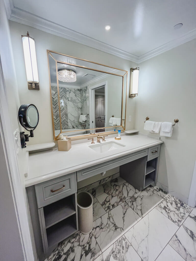 black and white marble bathroom with sink, large mirror, and storage at Disney's Riviera Resort.