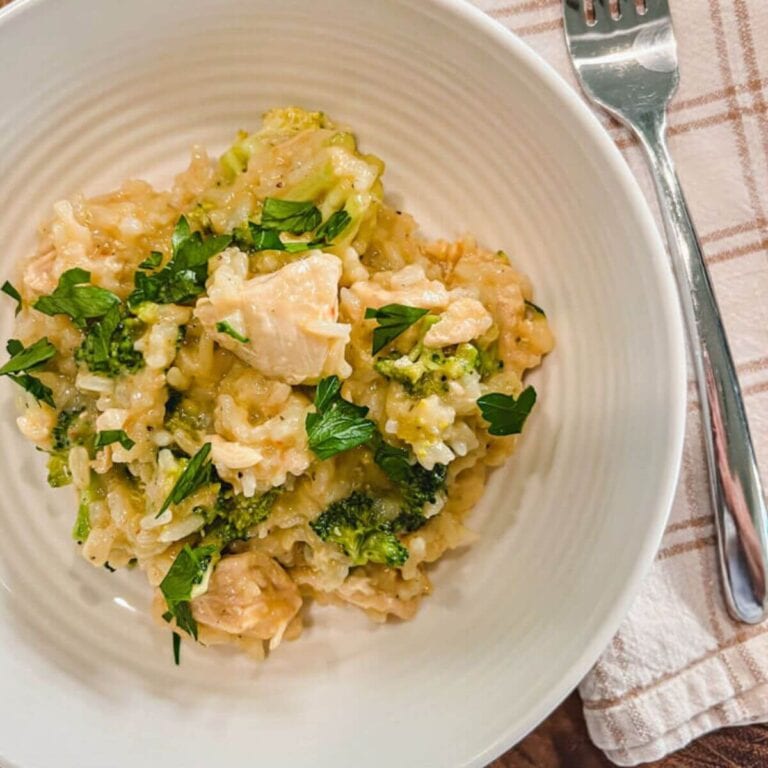 easy instant pot chicken and rice casserole served in a white bowl with a fabric napkin and fork next to the bowl.