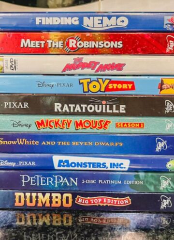 a stack of Disney movies on a black counter top.