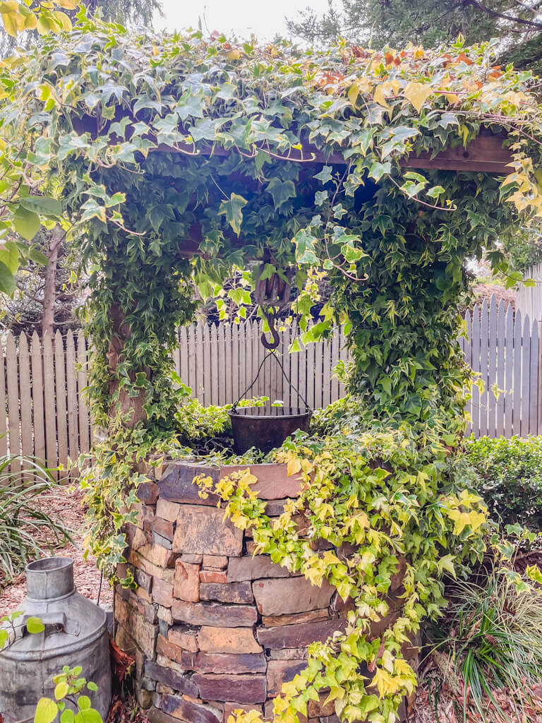 water well adorned in vines and plants in the gardens at Cambria Pines Lodge.