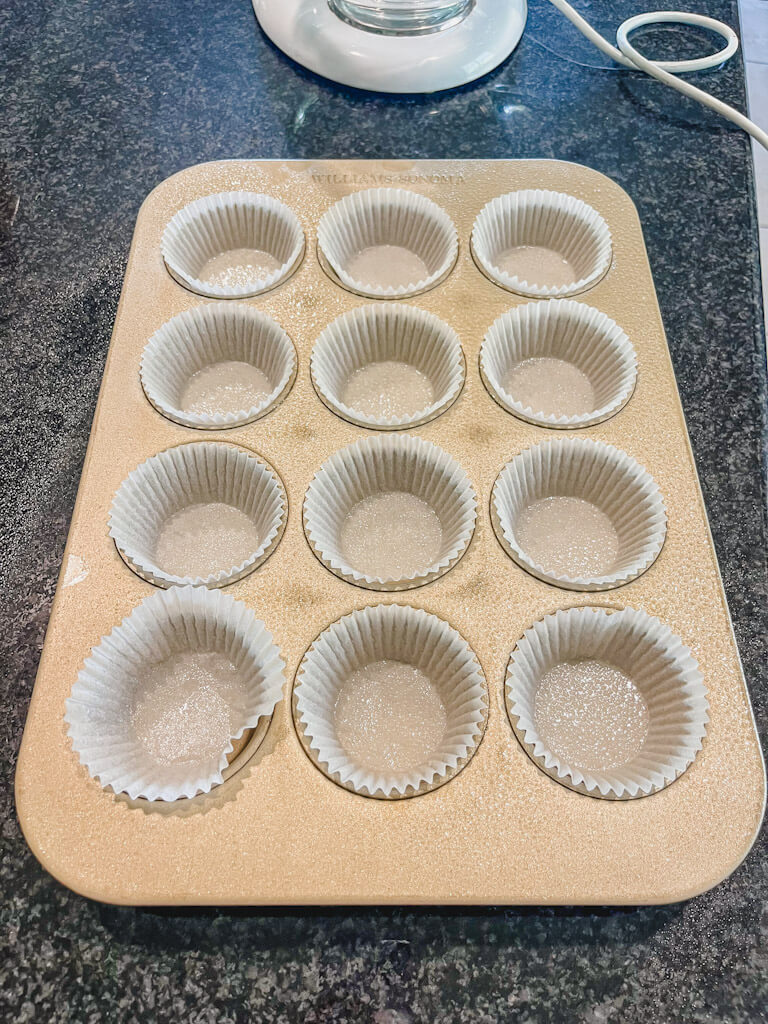 muffin liners inside a muffin tin on top of a black countertop.