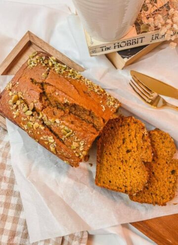 starbucks copycat pumpkin loaf on a wooden serving board with a stack of books in the background.
