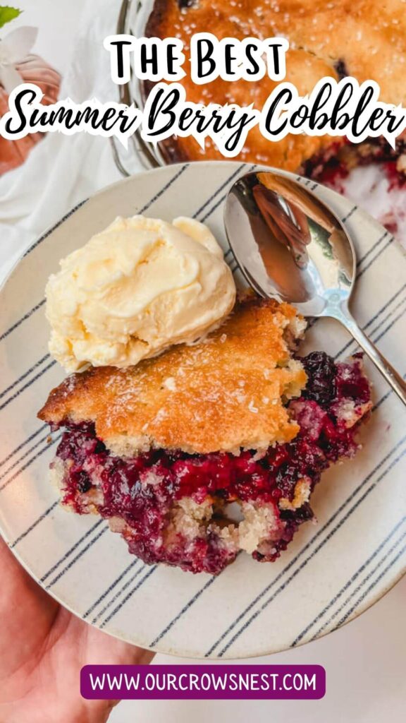 summer berry cobbler on a plate with a scoop of ice cream next to a spoon.