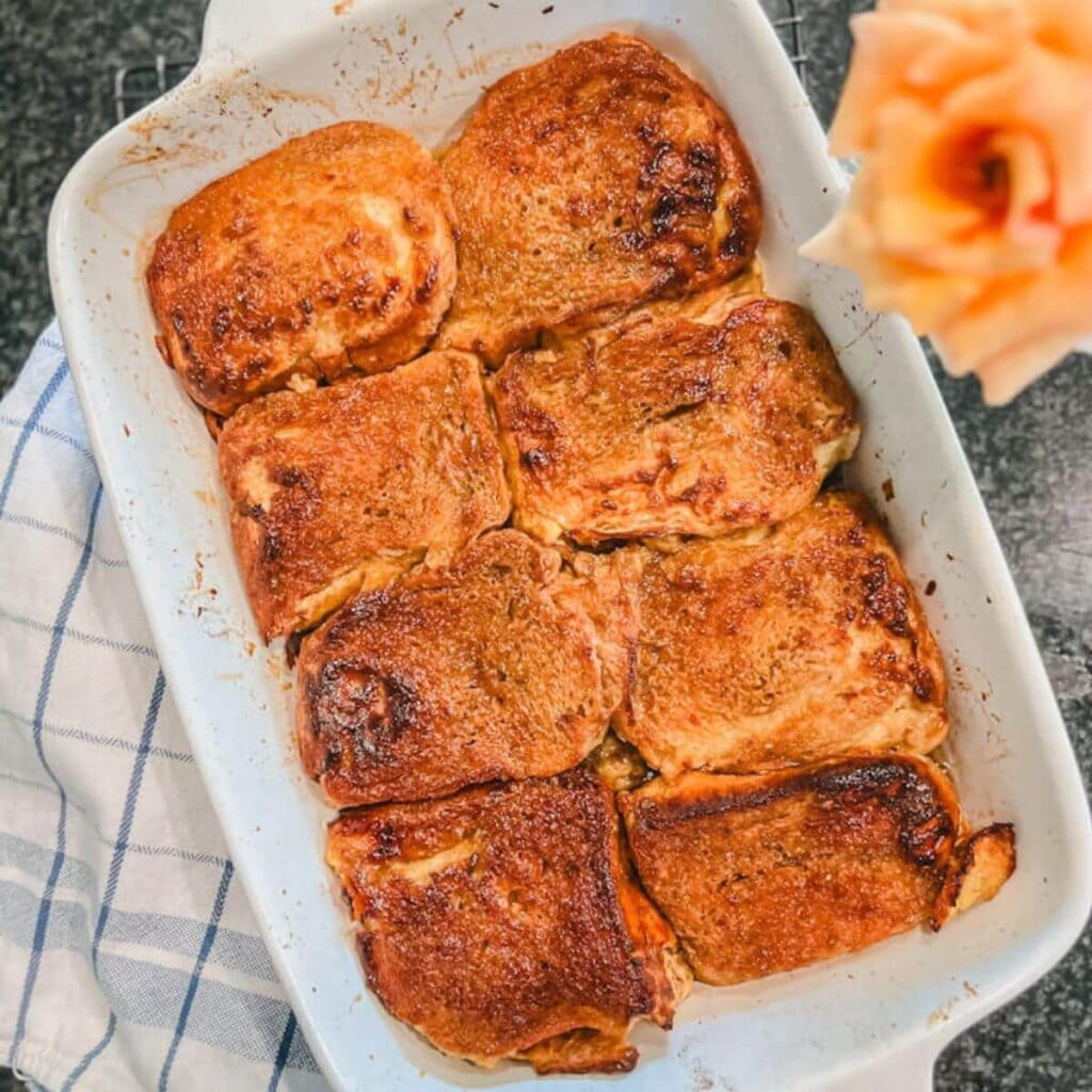 overhead picture of overnight baked creme brulee french toast in a white baking dish on the counter.