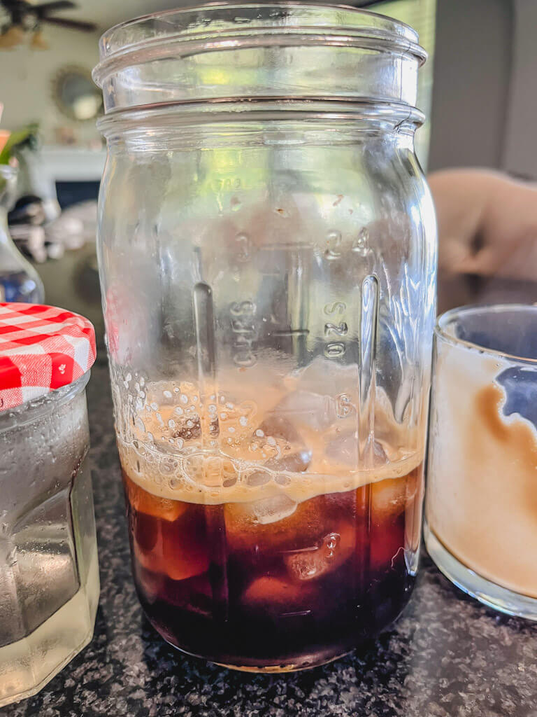 espresso poured into a tall mason jar with ice and simple syrup next to the jar.