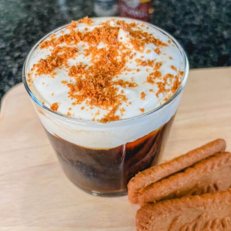 close up of white chocolate cold brew in a glass with cookies next ot the coffee.
