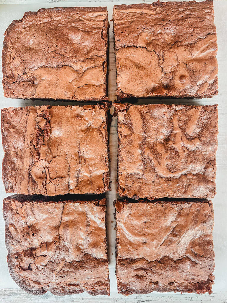 6 brownies cut into squares on a piece of parchment paper.