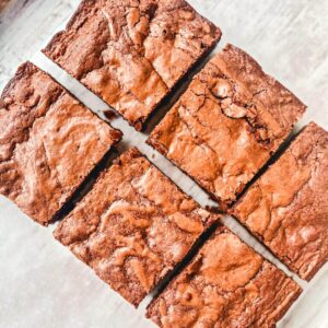 overhead picture of 6 lunchbox brownies cut into squares on a parchment paper.