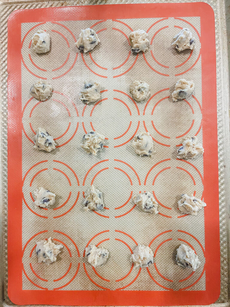 teaspoonfuls of cookie dough dropped onto silicone baking mats ready to be baked or frozen.