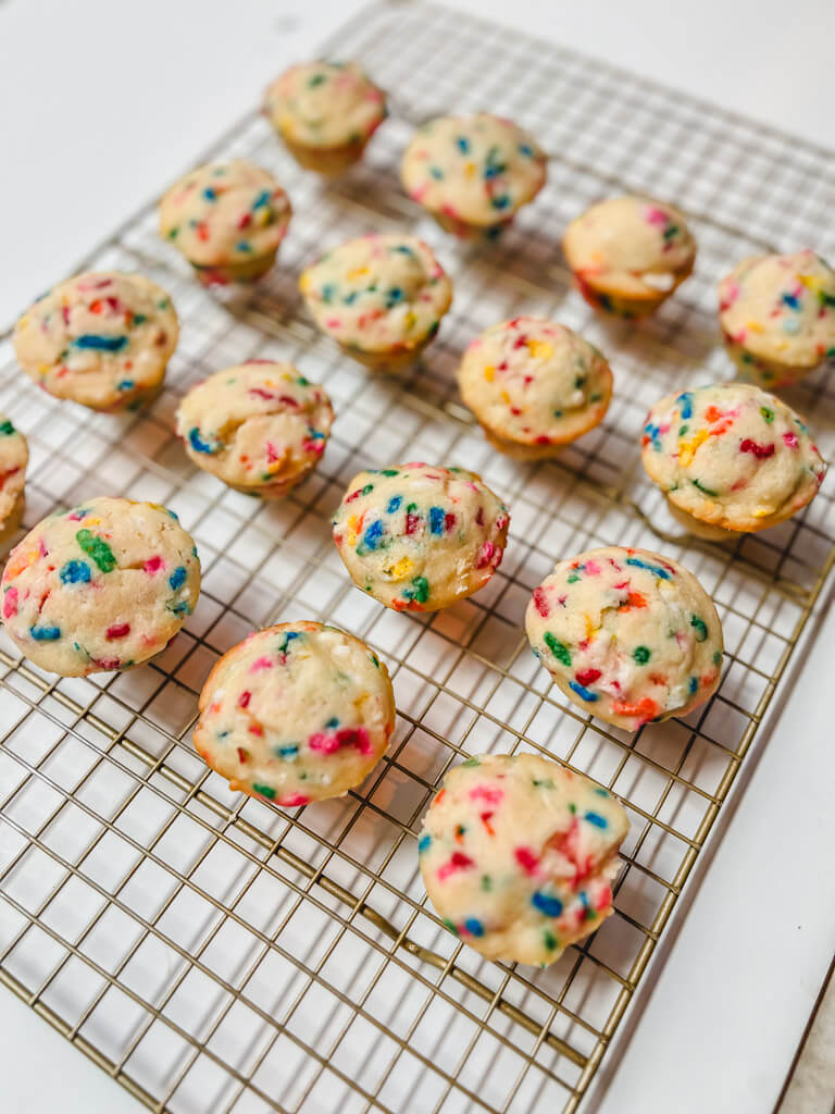 16 mini funfetti cupcakes on a cooling rack on a white background. 