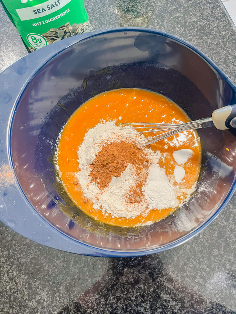 dry ingredients being added to the wet ingredients in a mixing bowl.