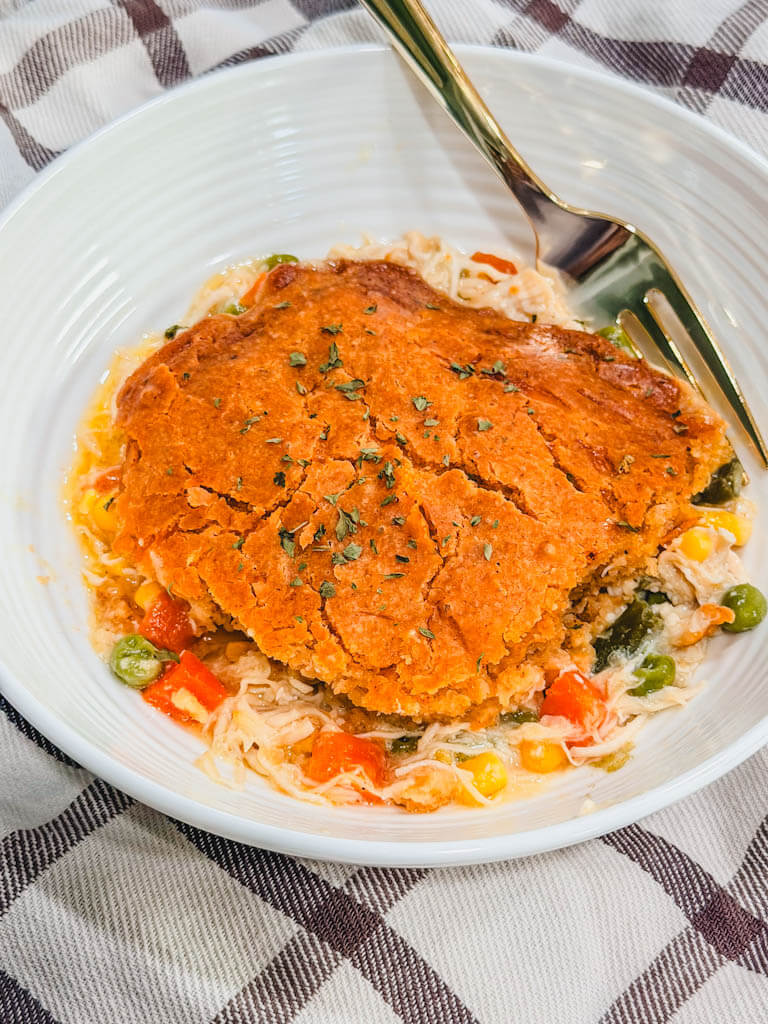 overhead view of a serving of red lobster chicken biscuit cobbler in a white bowl with a fork. 