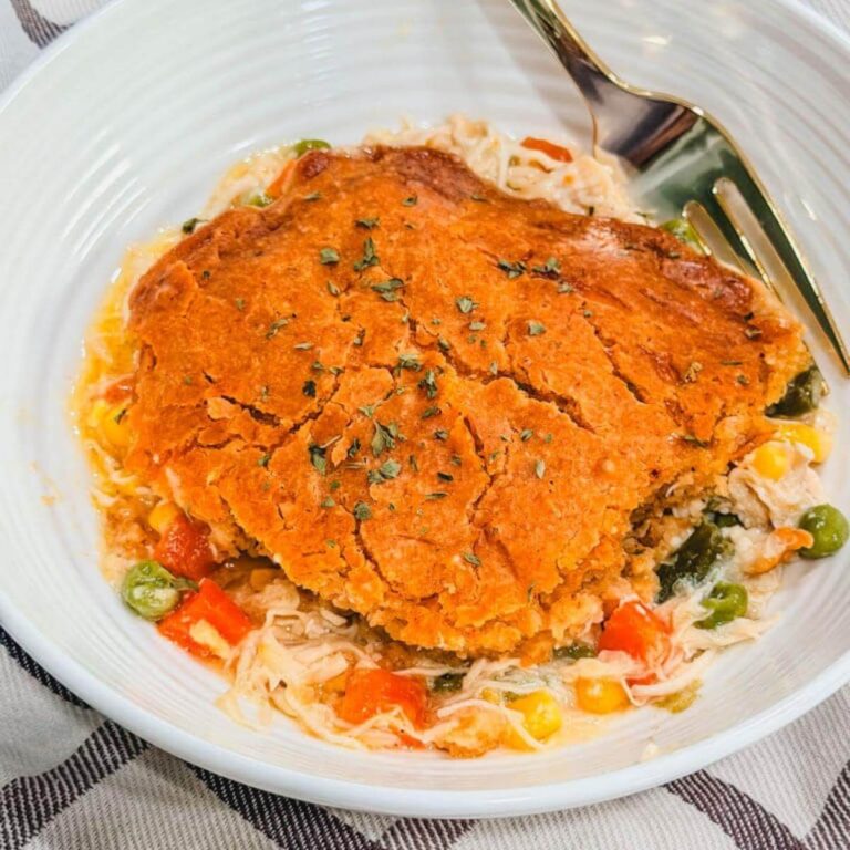 close up of a serving of red lobster chicken biscuit cobbler in a white bowl with parsley on top.