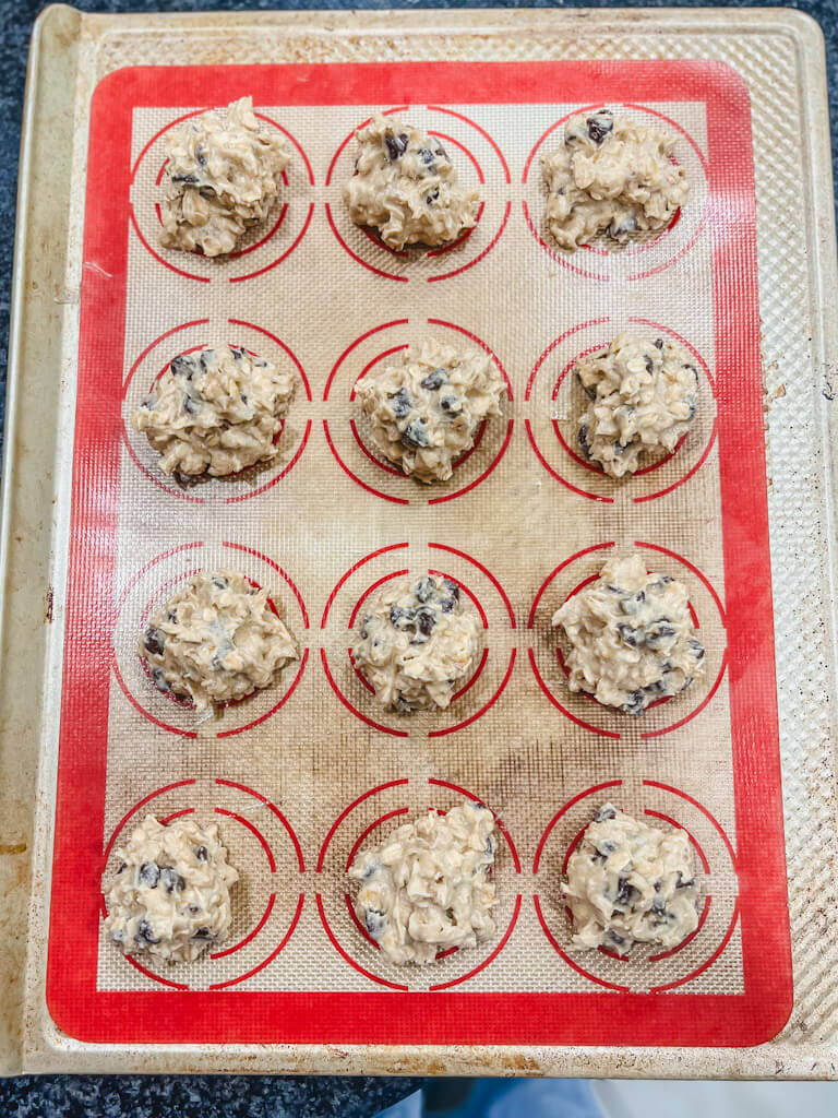 tablespoonfuls of the banana bread muffin top dough on a baking sheet line with a silicone mat.
