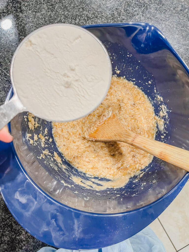 all purpose flour about to be added to the blue mixing bowl with the wet ingredients.