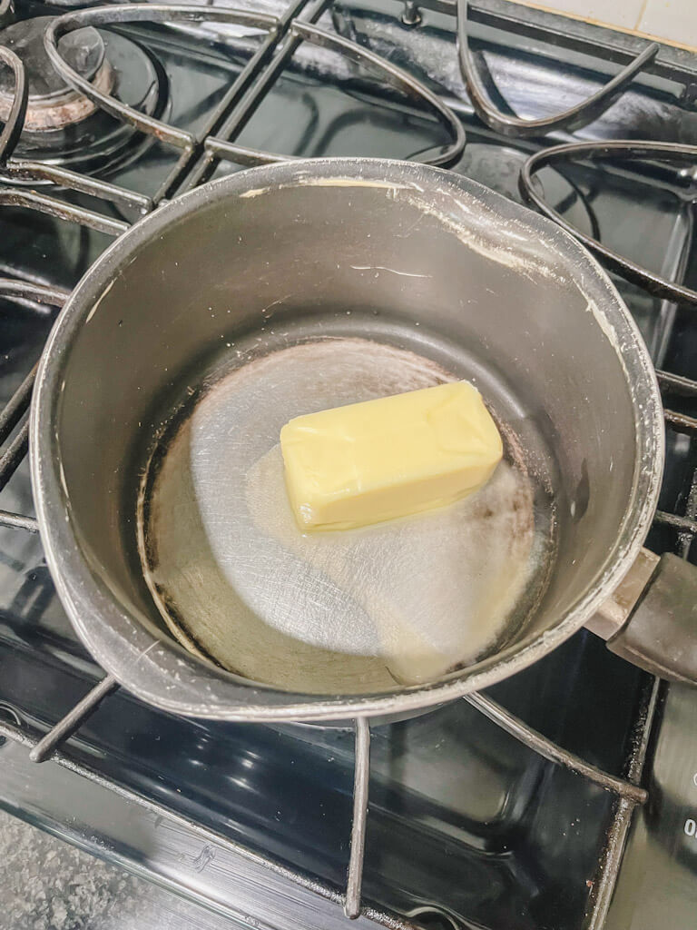 1 stick of butter being melted in a saucepan on the stovetop.