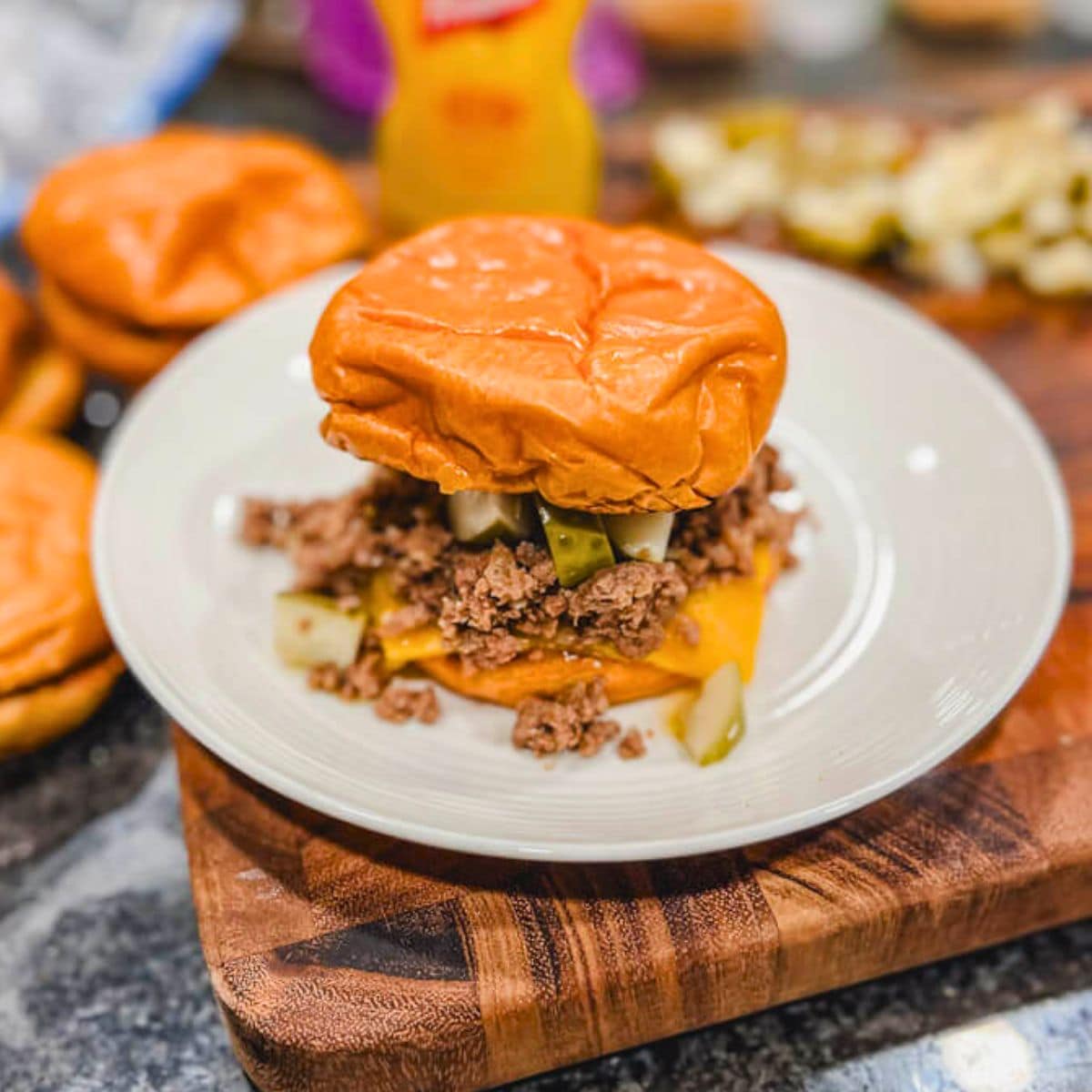 roseanne's loose meat tavern sandwiches on a white plate on top of a wooden cutting board.