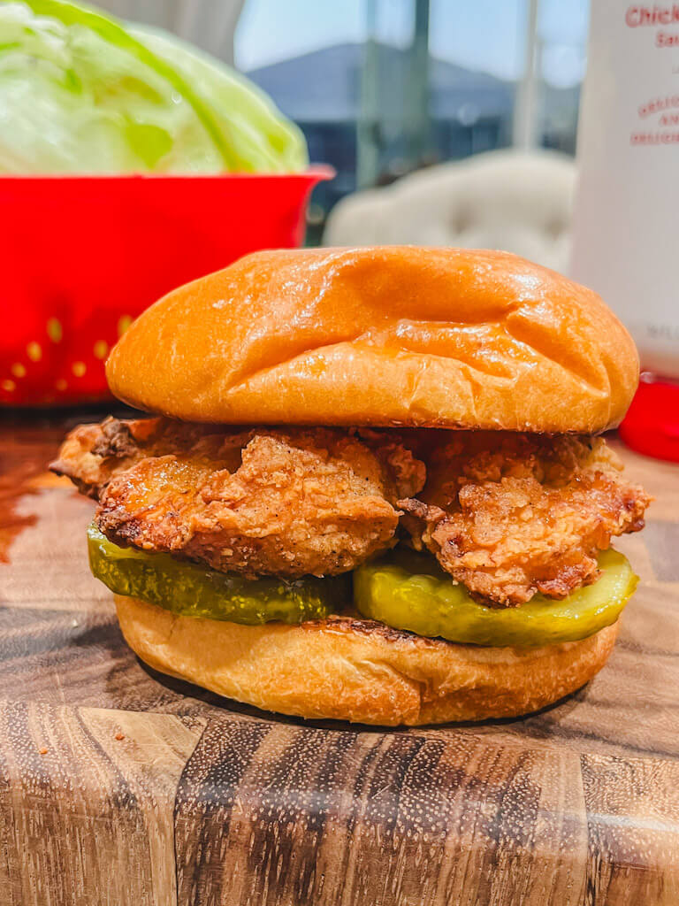 an aldi copycat chick-fil-a chicken sandwich made in the air fryer resting on a wooden cutting board.