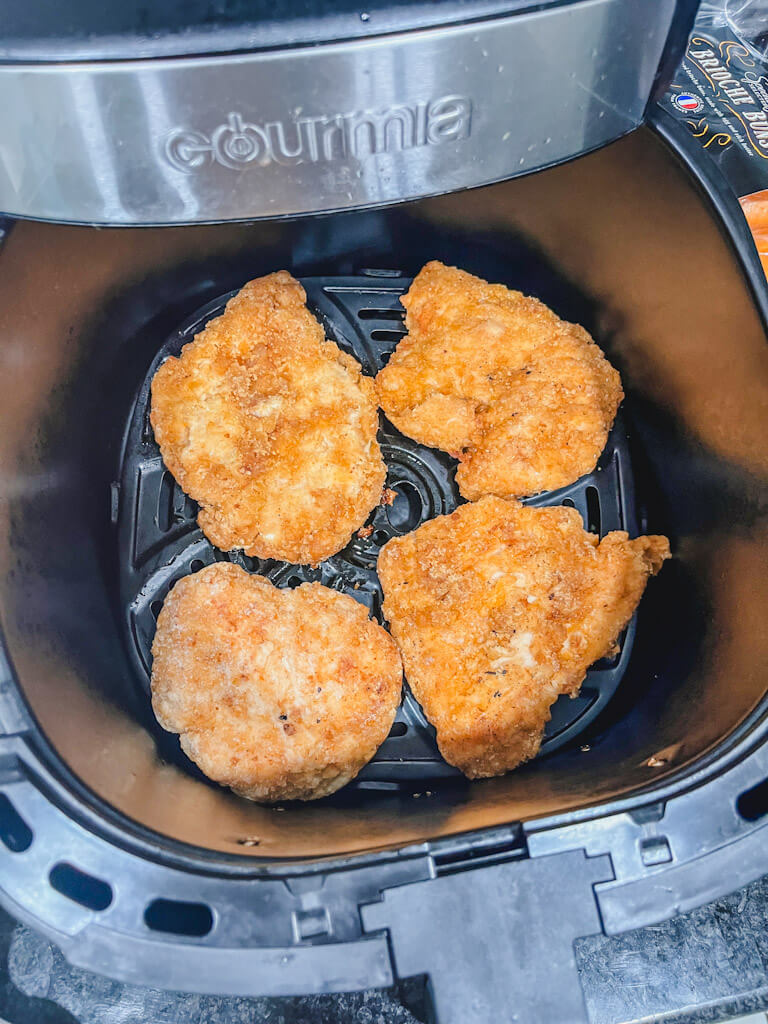 4 frozen breaded chicken fillets in the air fryer ready to be cooked.