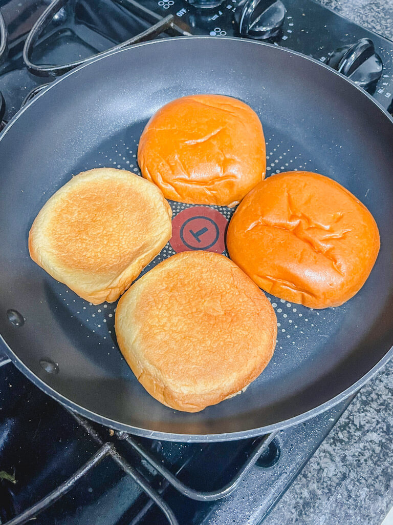 2 sets of brioche buns toasting on a skillet on the stove top.
