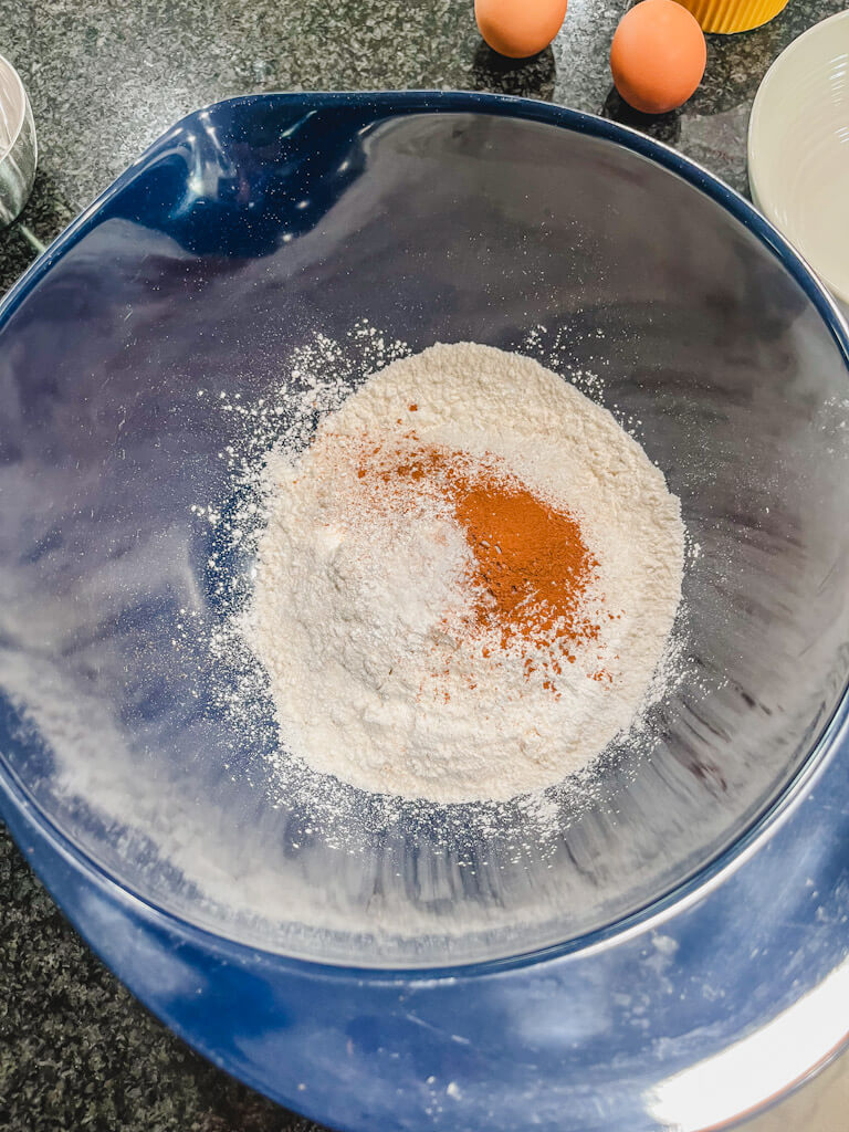 flour, sugar, cinnamon, salt, and baking powder added to a blue mixing bowl.