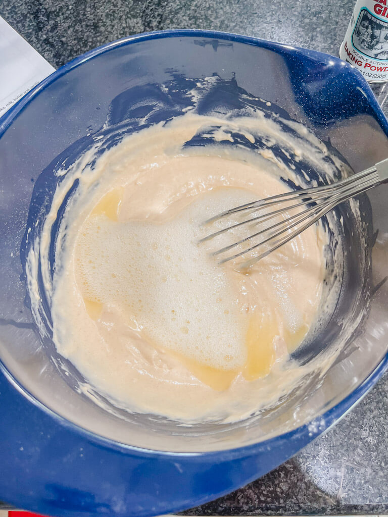 a whisk about to mix the egg whites together with the wet ingredients in a blue mixing bowl.