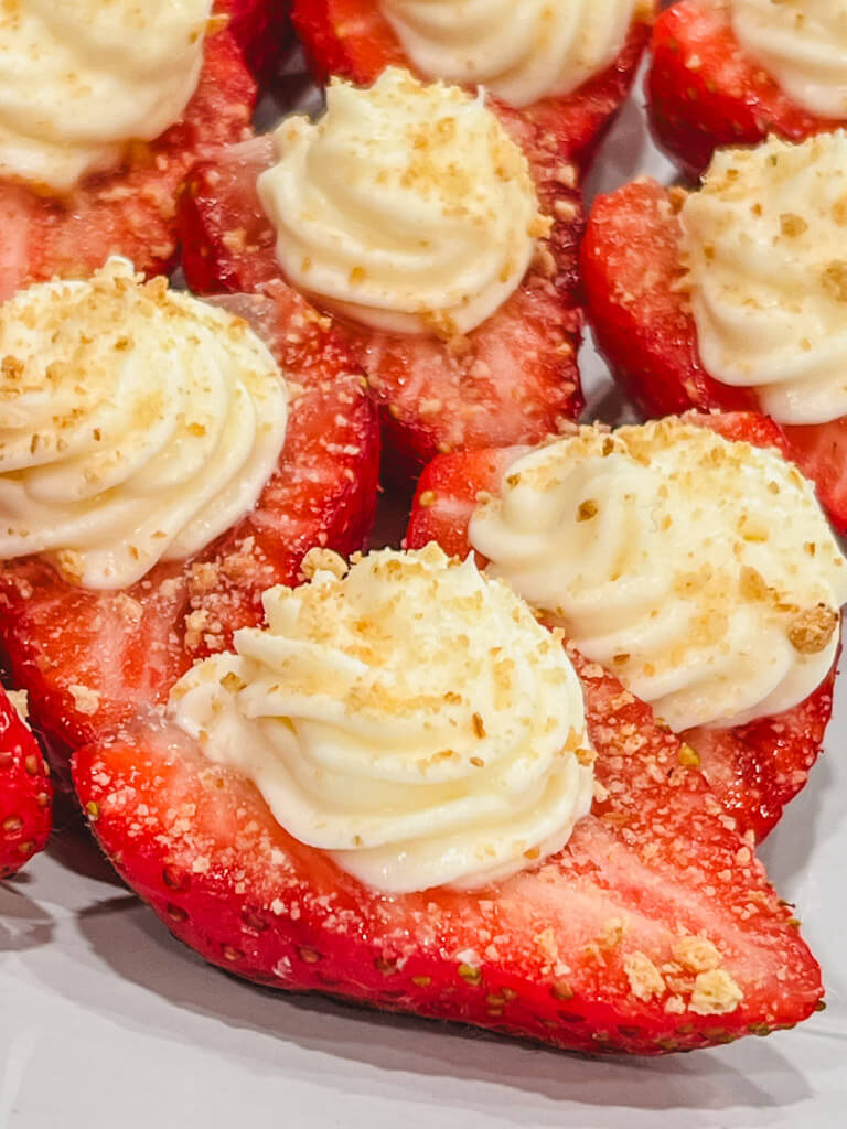 close up of a few deviled strawberries on a white platter.