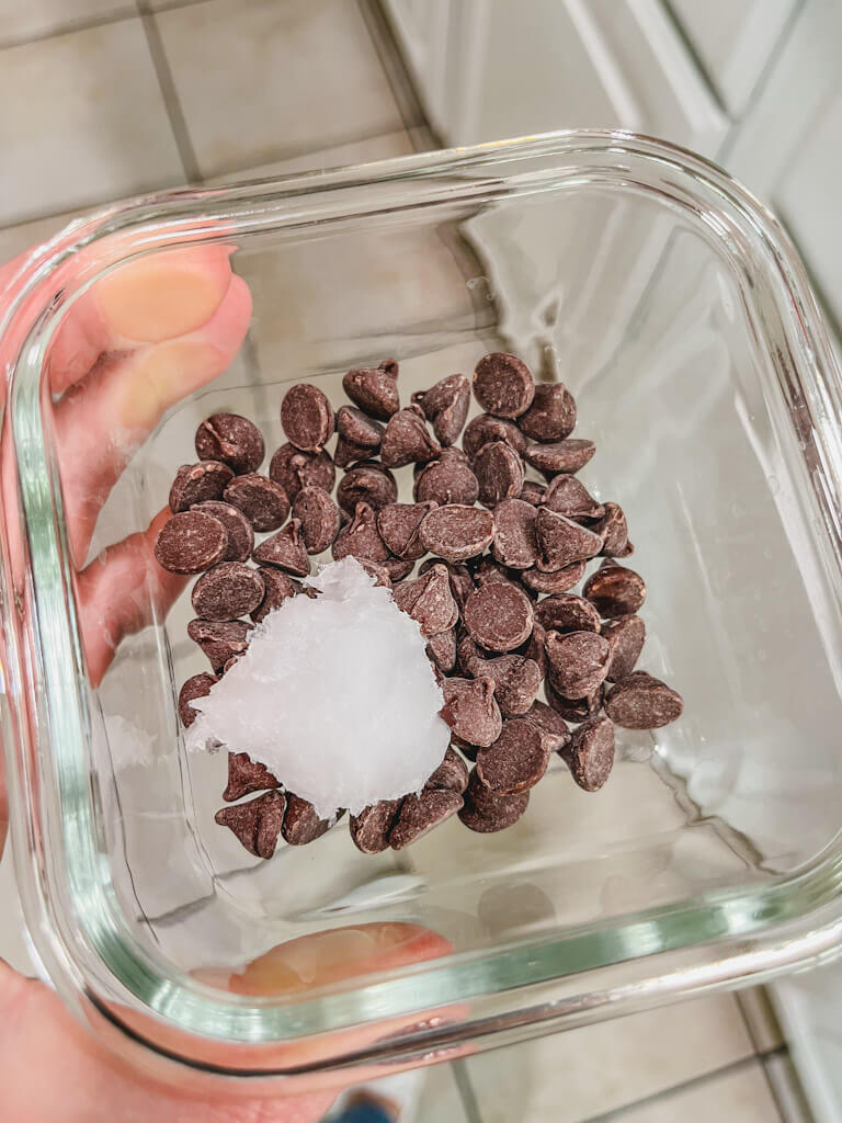 chocolate chips in a small glass bowl with cocount oil.