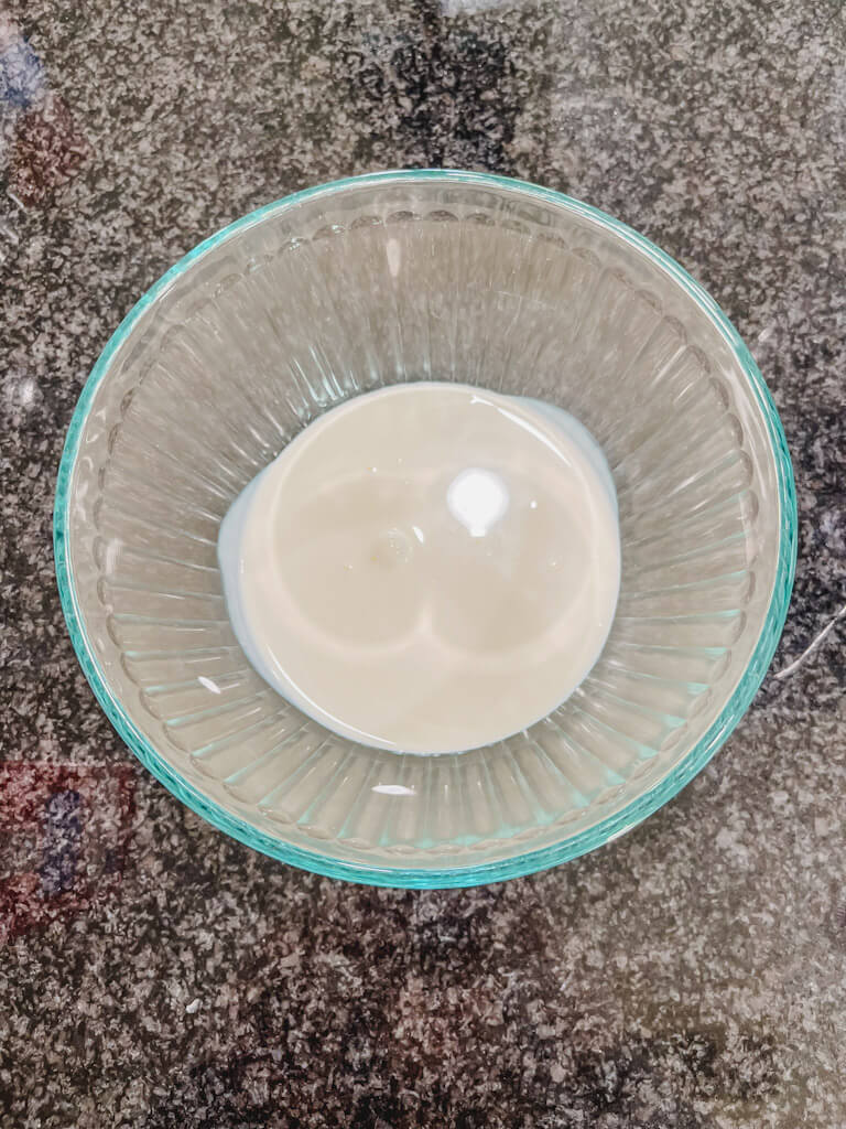 heavy cream added to a clear glass bowl.