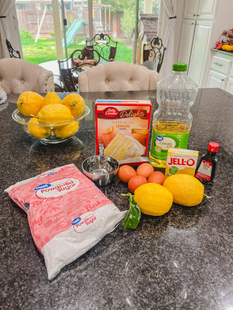 ingredients for old fashioned jello lemon cake laid out on a black counter top.