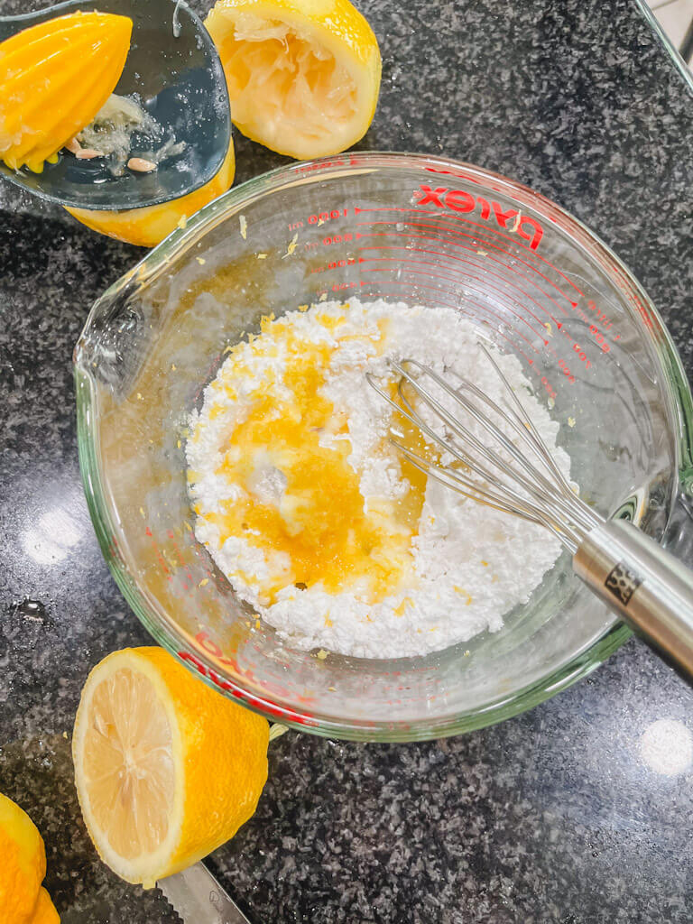 Powdered sugar, lemon juice, and lemon zest added into the melted butter about to be whisked together.