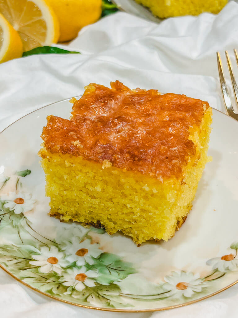 a slice of old fashioned jello lemon cake on a small daisy plate.