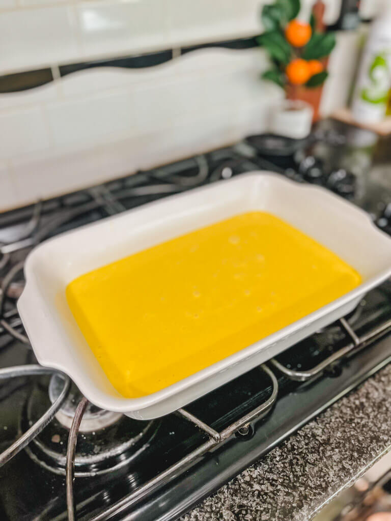 old fashioned jello lemon cake batter in a white ceramic baking dish about to go into the oven.
