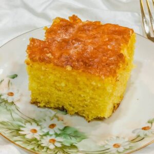 old fashioned lemon jello cake slice on a small dainty daisy decorated plate.