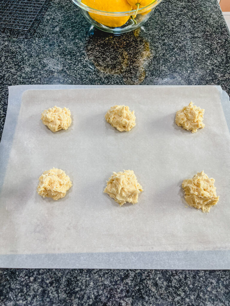 6 cookie dough mounds on a cookie sheet bound for the oven.