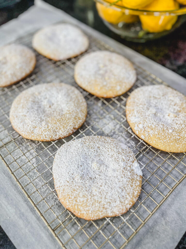 panera lemon drop cookies on a wire rack with powdered sugar on top.